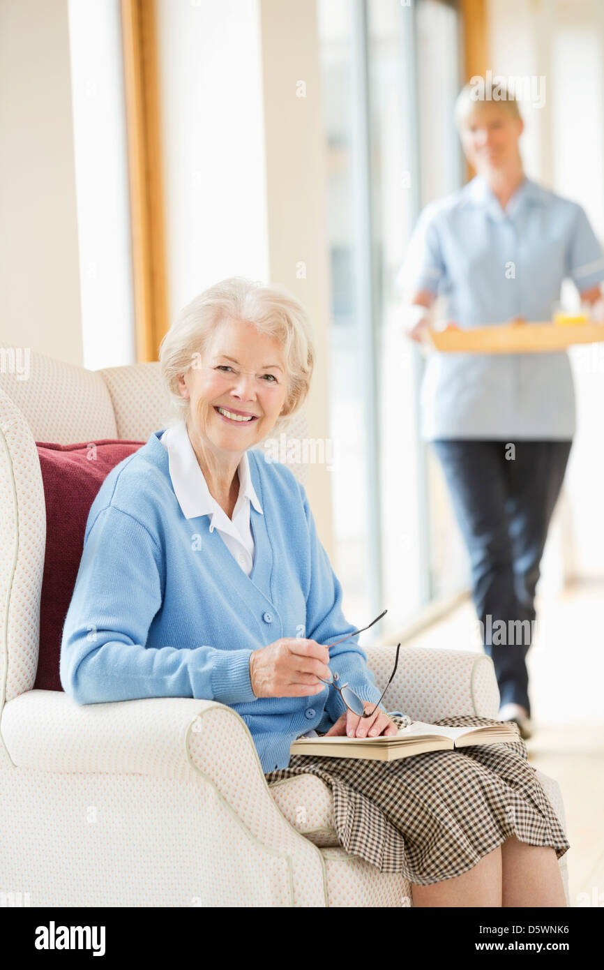 Older woman smiling in armchair Stock Photo