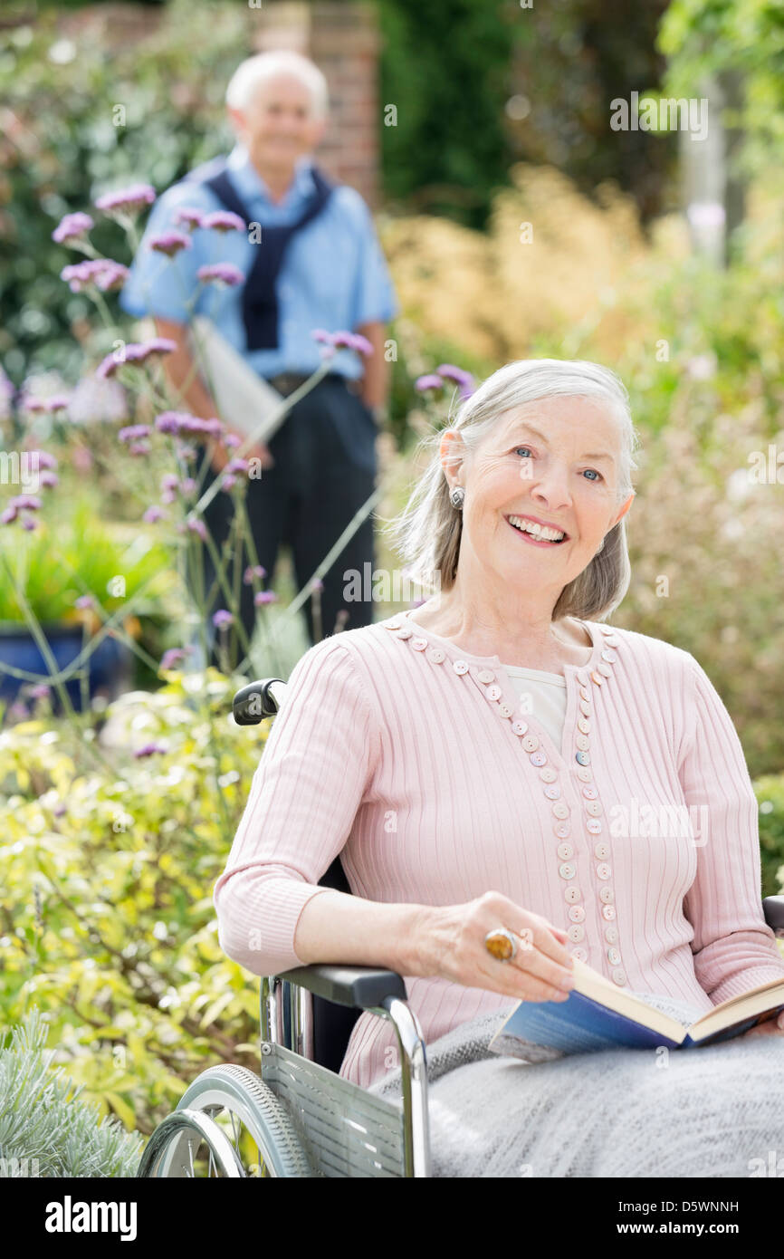 Older woman in wheelchair reading outdoors Stock Photo