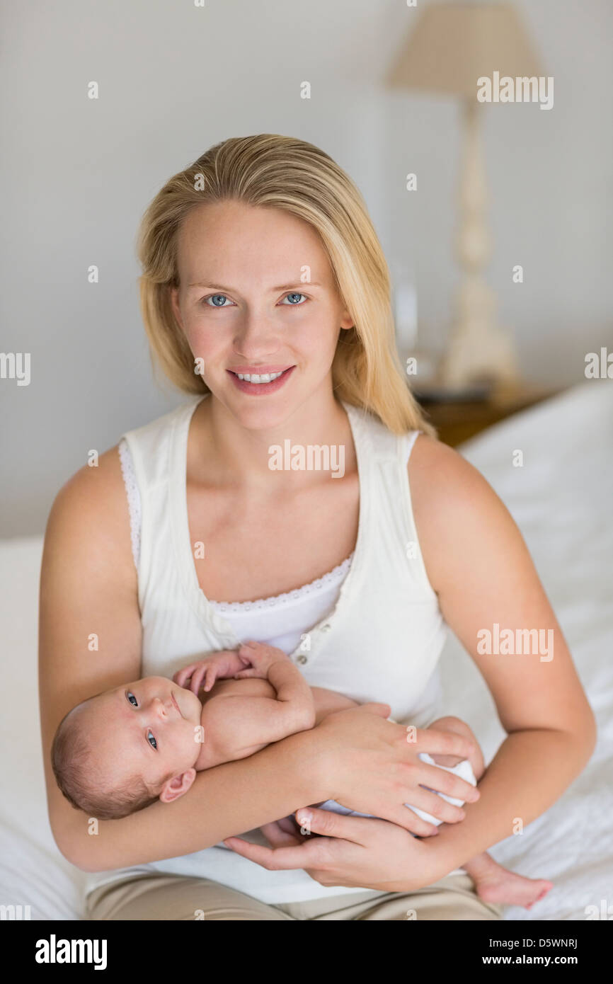 Mother cradling newborn baby on bed Stock Photo Alamy