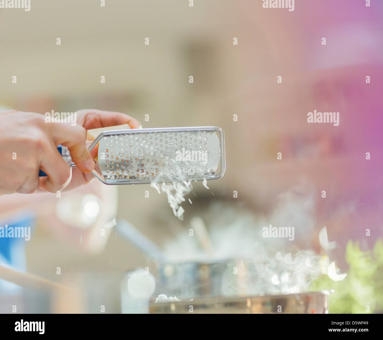 Woman grating cheese in kitchen Stock Photo