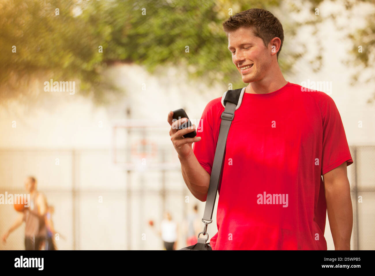 Man using cell phone on basketball court Stock Photo Alamy