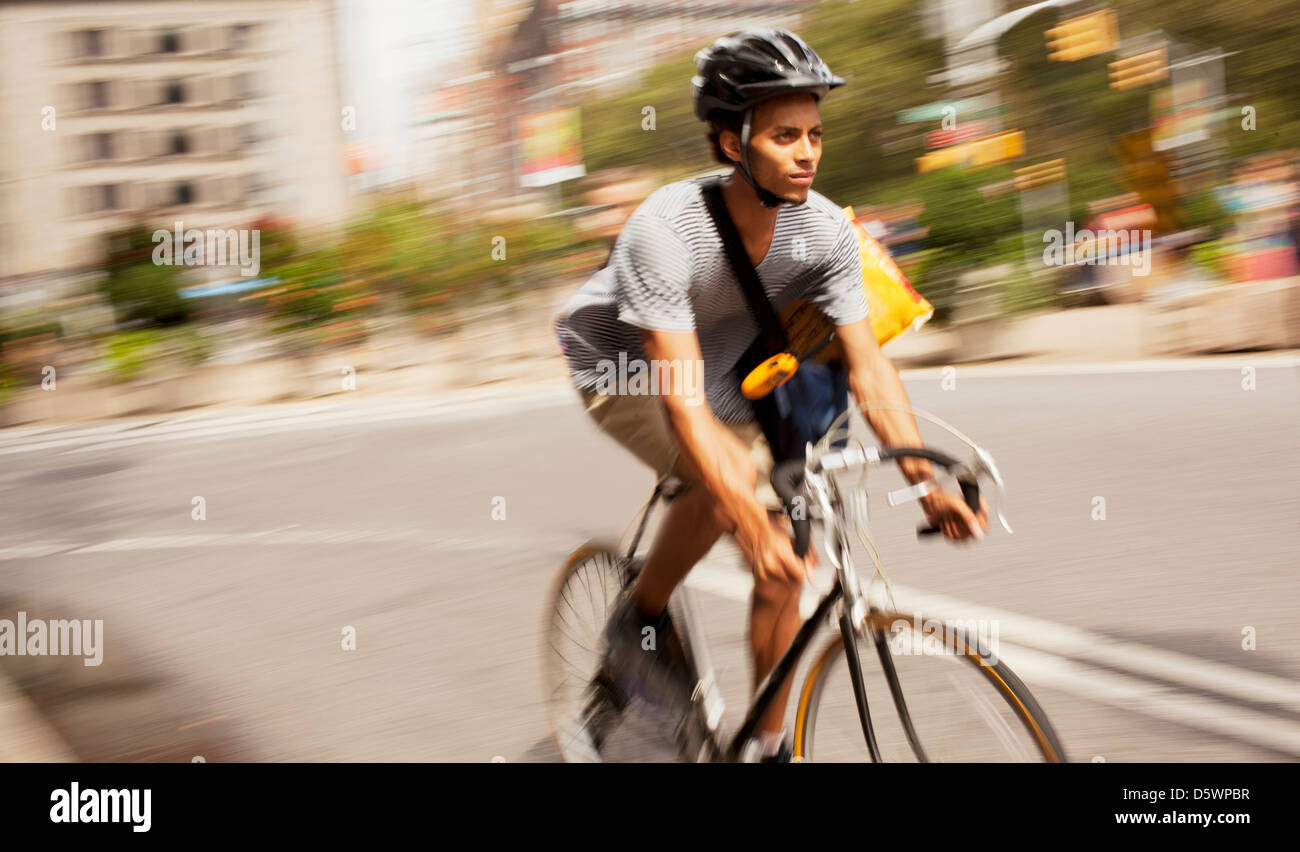 Man riding bicycle on city street Stock Photo