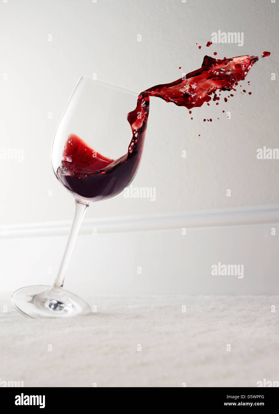 Glass of red wine spilling Stock Photo
