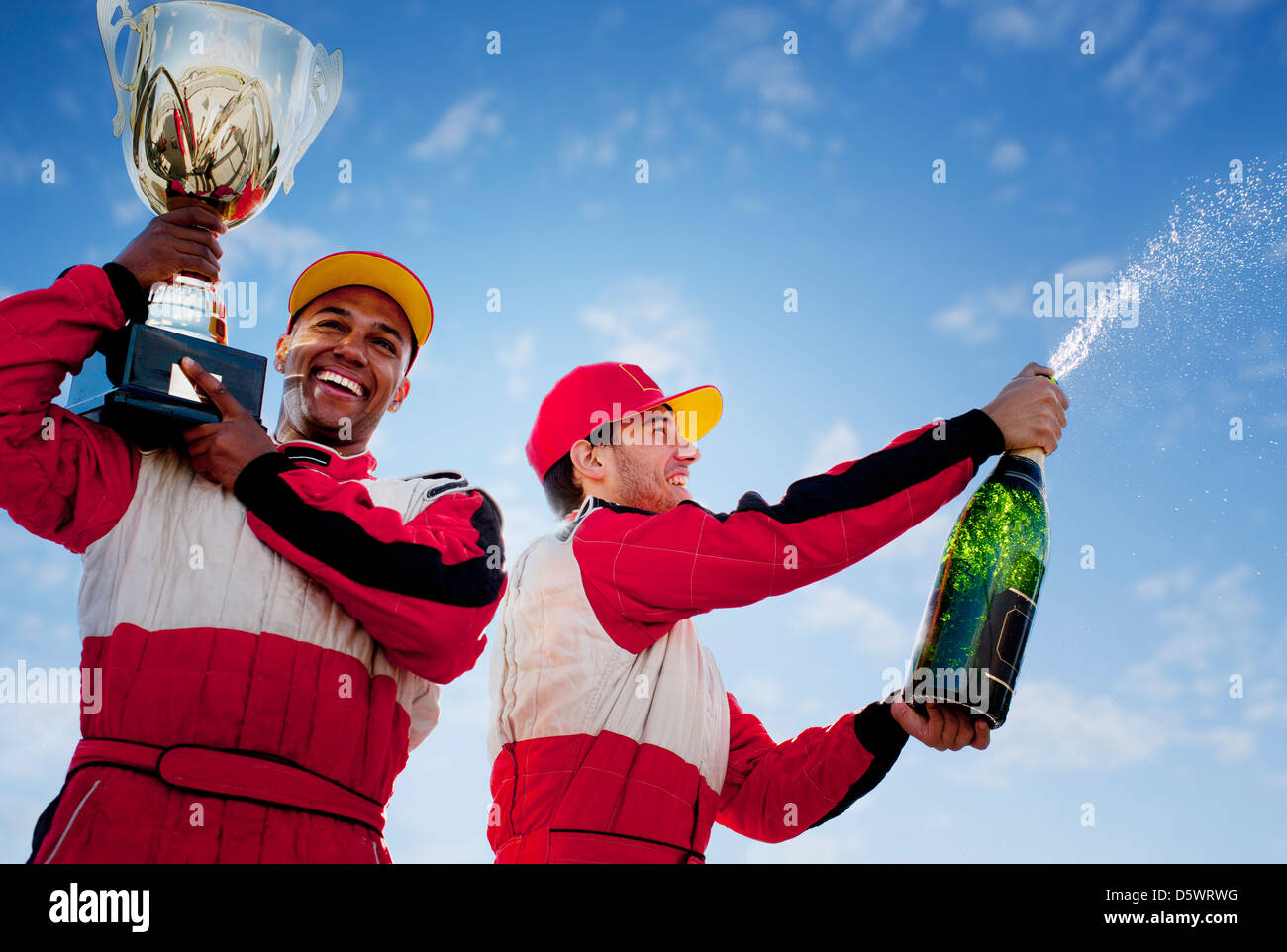 Racers holding trophy and champagne Stock Photo