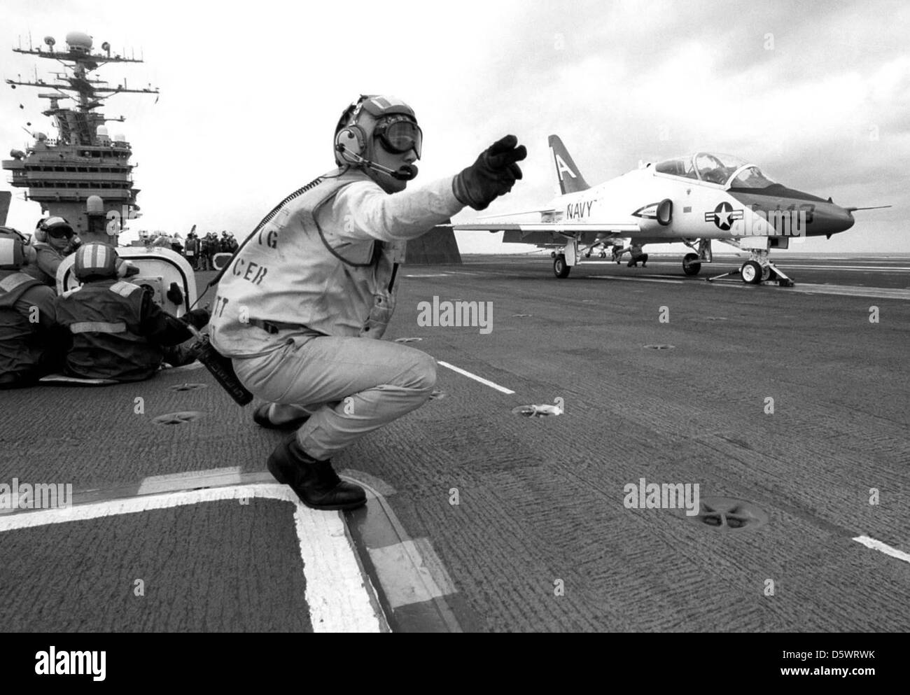 US Navy (USN) Lieutenant Commander (LCDR) Sherman Scott, a Aircraft Handling Officer, gives the launch signal to a USN T-45A Goshawk aircraft from Training Squadron Seven (VT-7), as the aircraft prepares to launch, during final qualifications aboard the USN Aircraft Carrier USS GEORGE WASHINGTON (CVN-73). Stock Photo
