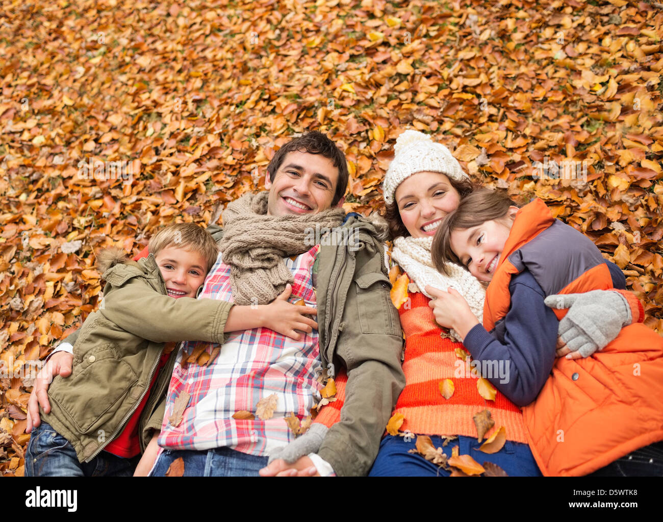 Smiling family laying in autumn leaves Stock Photo - Alamy