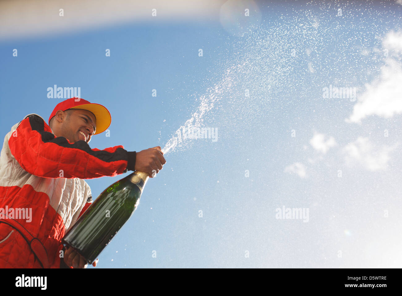 Racer spraying bottle of champagne outdoors Stock Photo