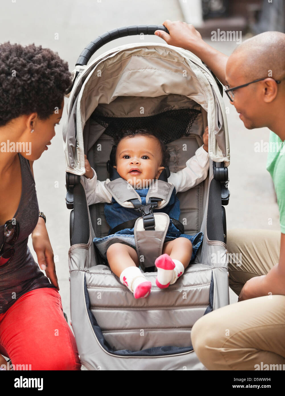 Parents with baby in stroller on city street Stock Photo