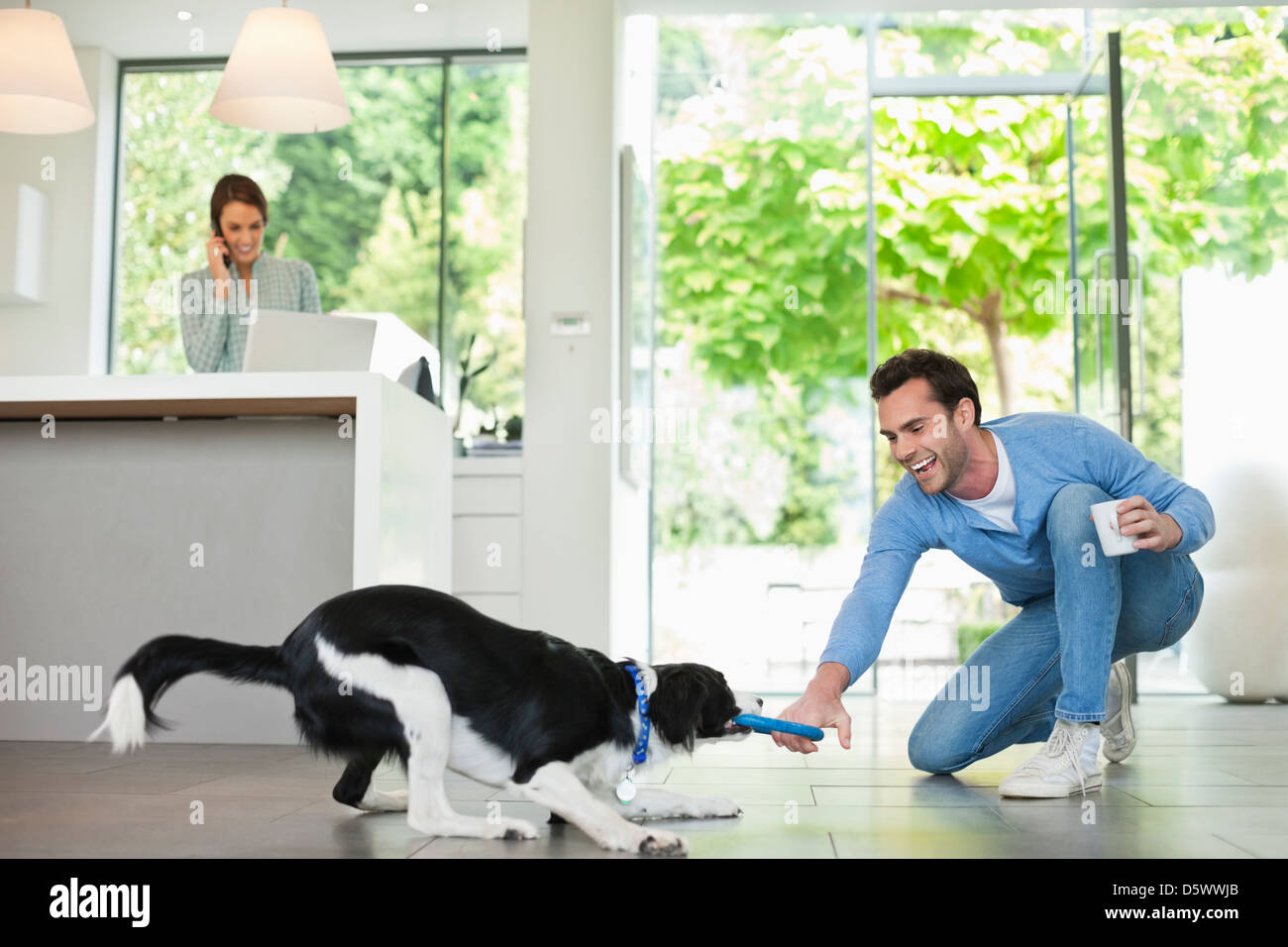Man playing with dog in kitchen Stock Photo
