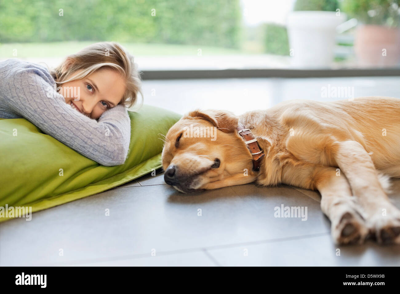 Smiling woman relaxing with dog on floor Stock Photo