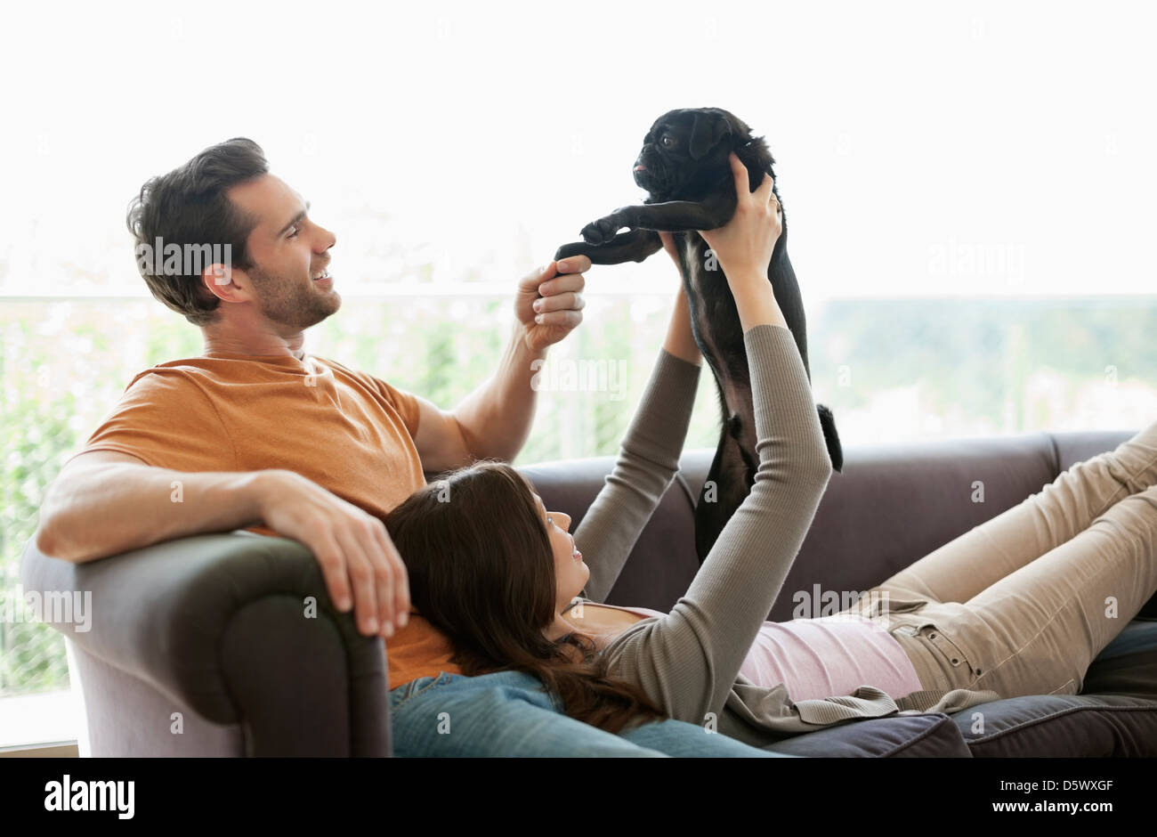 Couple relaxing with dog on sofa Stock Photo