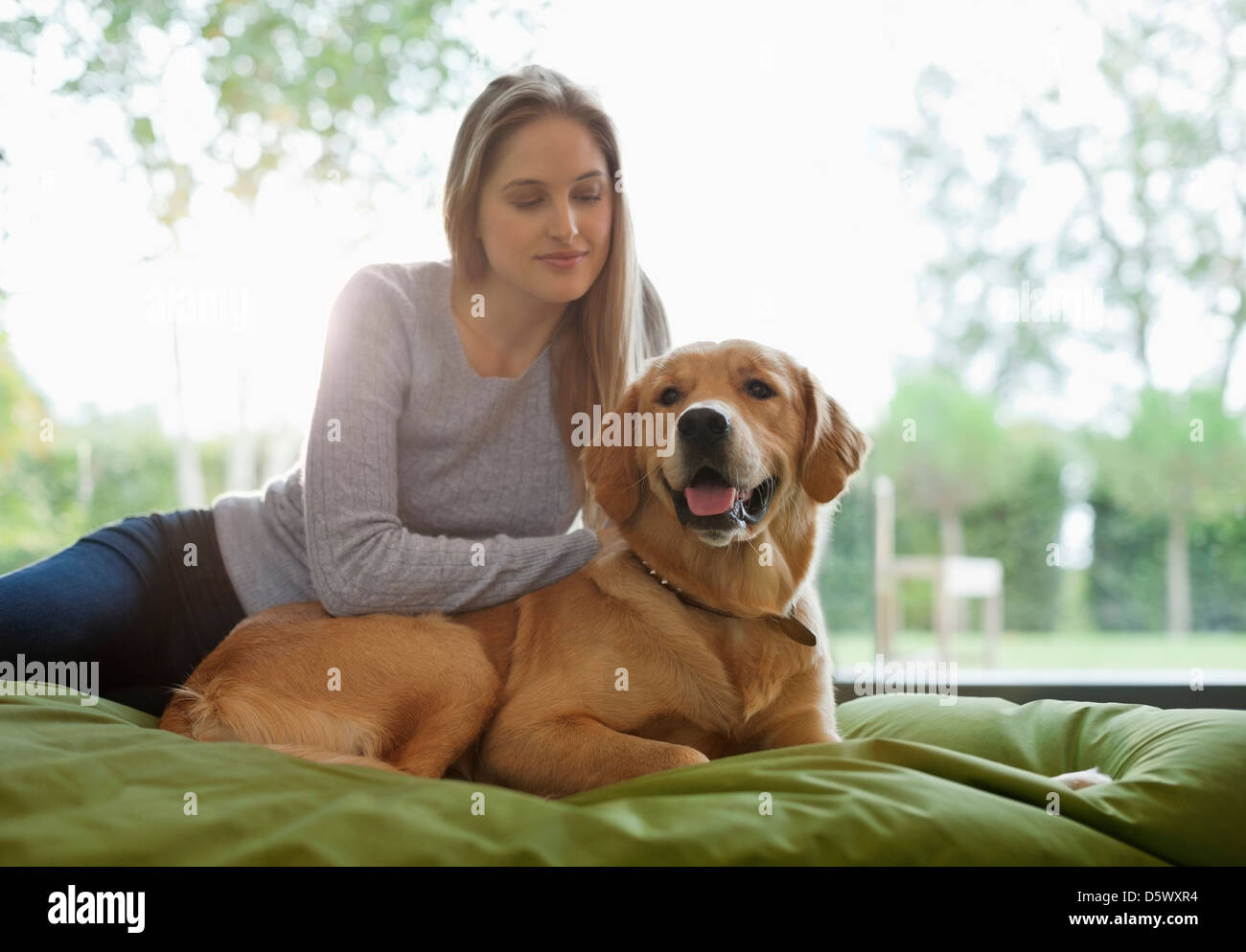 Woman petting dog on bed Stock Photo