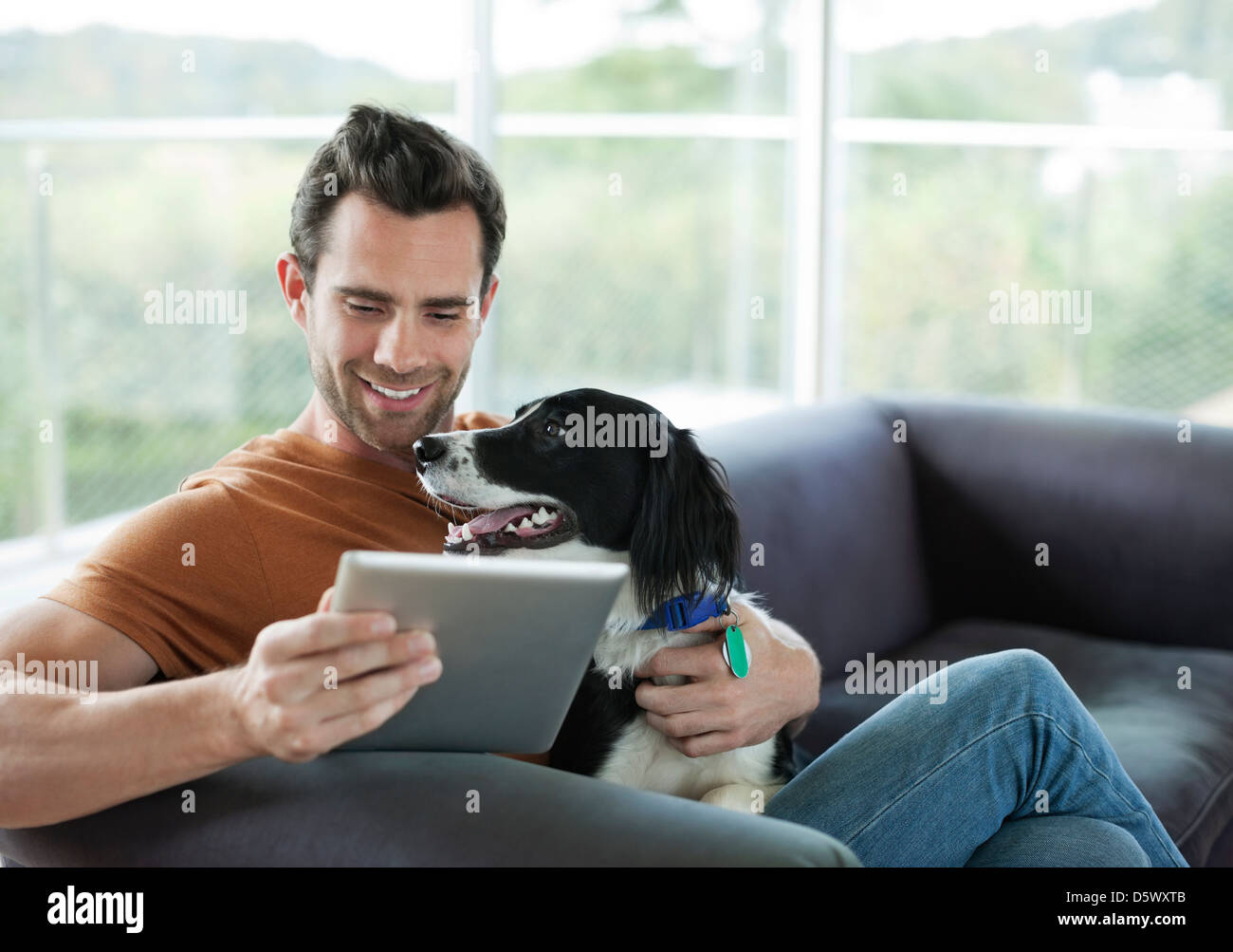 Man petting dog and using tablet computer Stock Photo