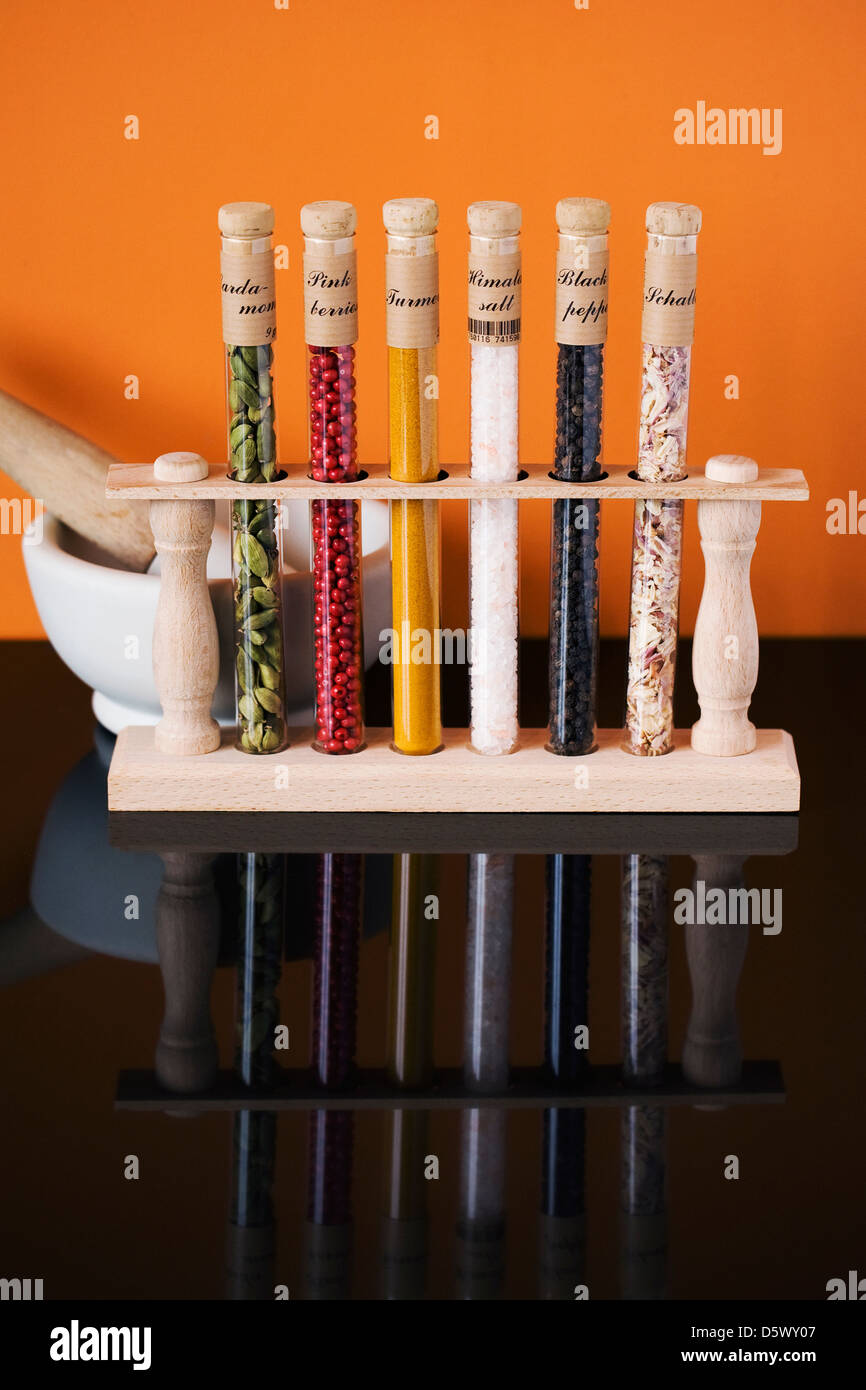 A selection of herbs and spices in glass tubes reflected in a black surface. Stock Photo