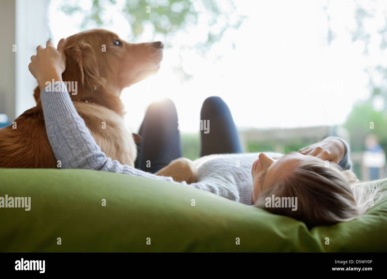 Woman petting dog on bed Stock Photo