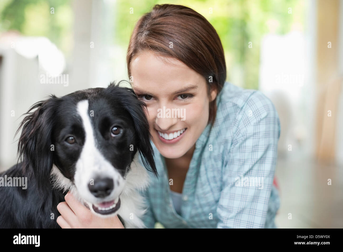 Smiling woman petting dog indoors Stock Photo