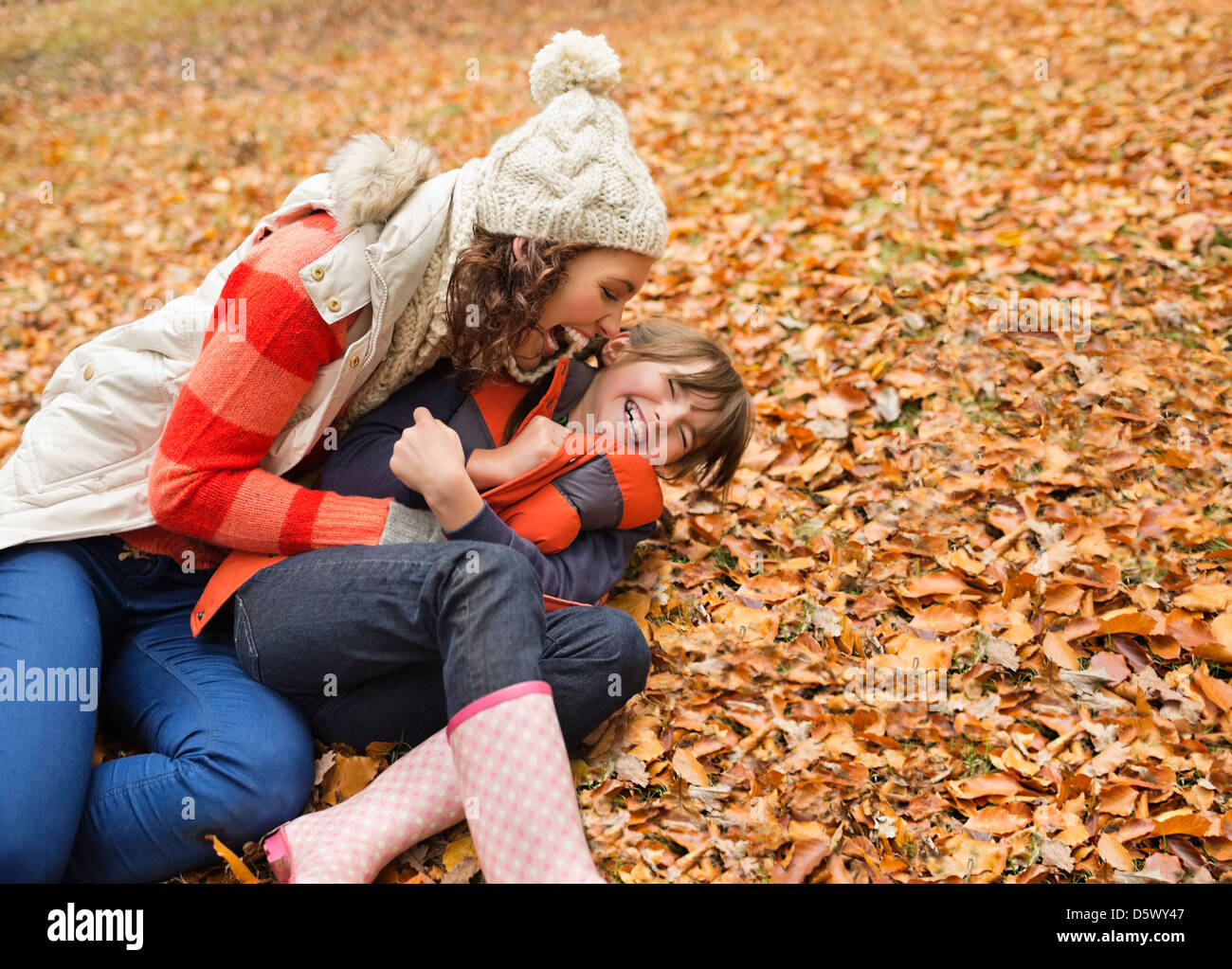 Mother and daughter playing in autumn leaves Stock Photo