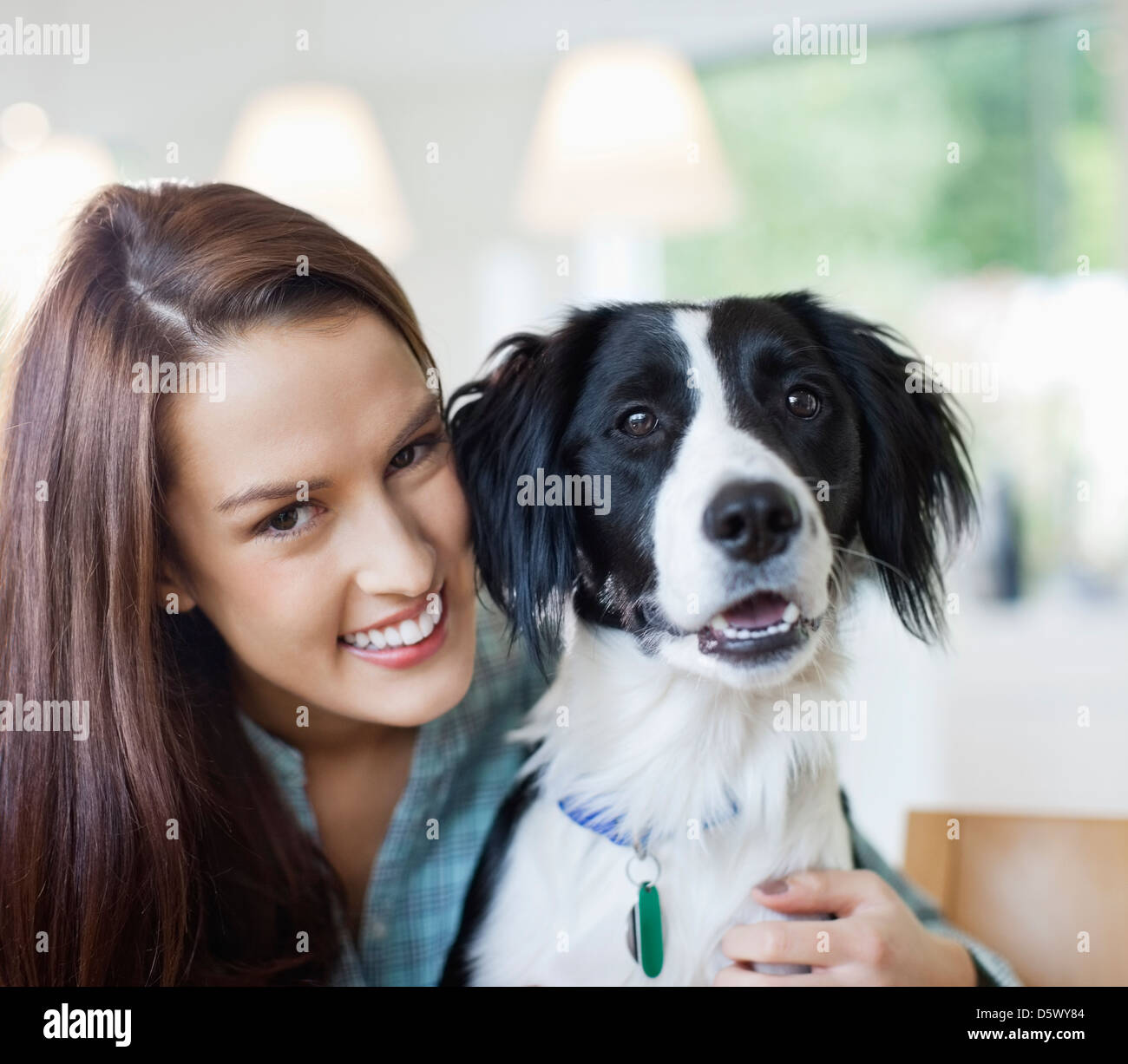 Smiling woman hugging dog indoors Stock Photo