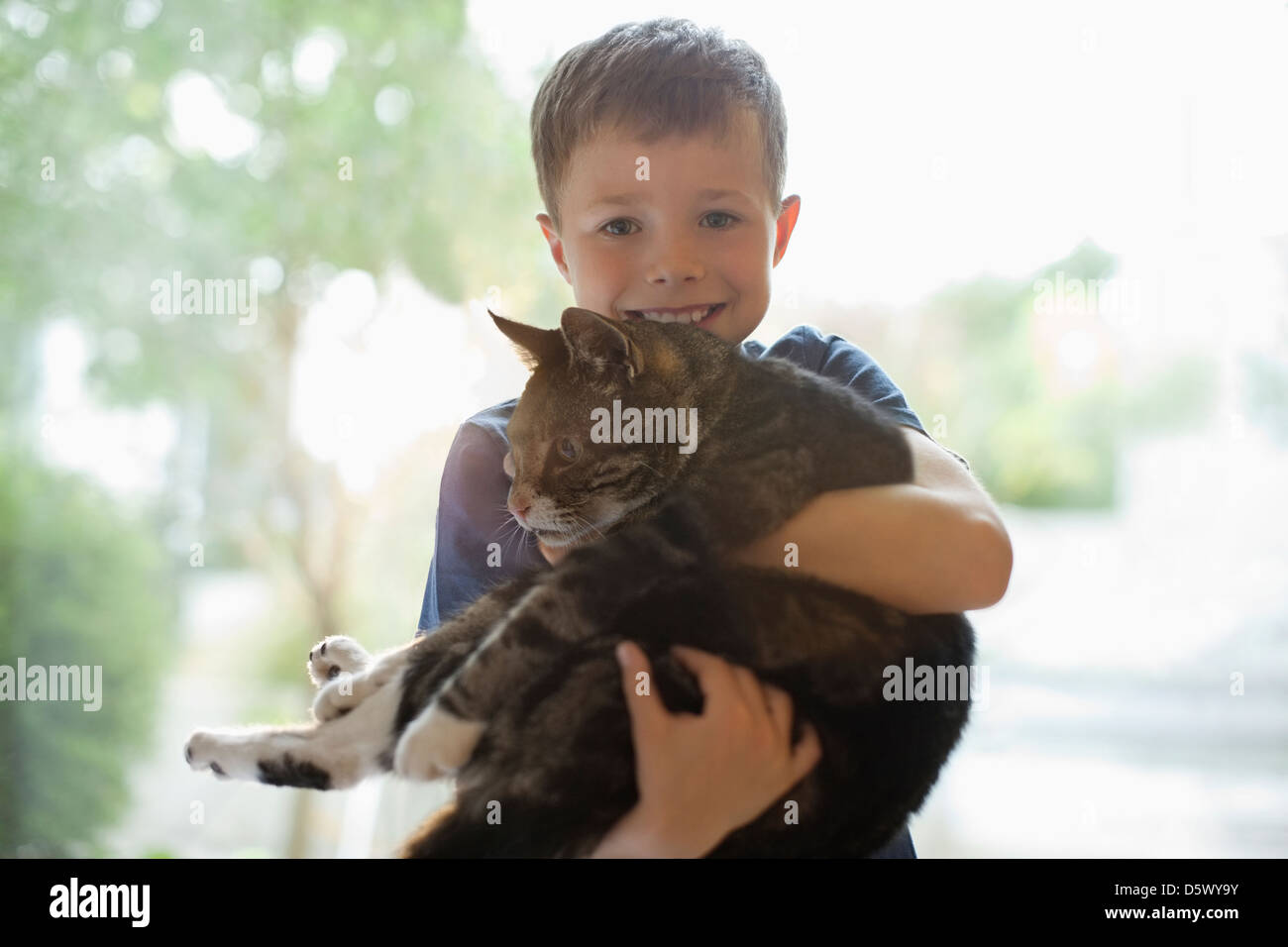 Smiling boy holding cat indoors Stock Photo