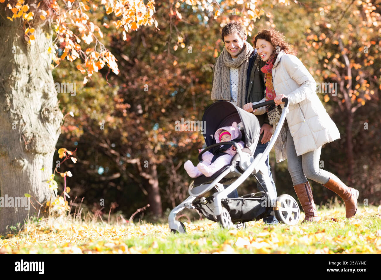 Couple pushing baby in stroller in park Stock Photo