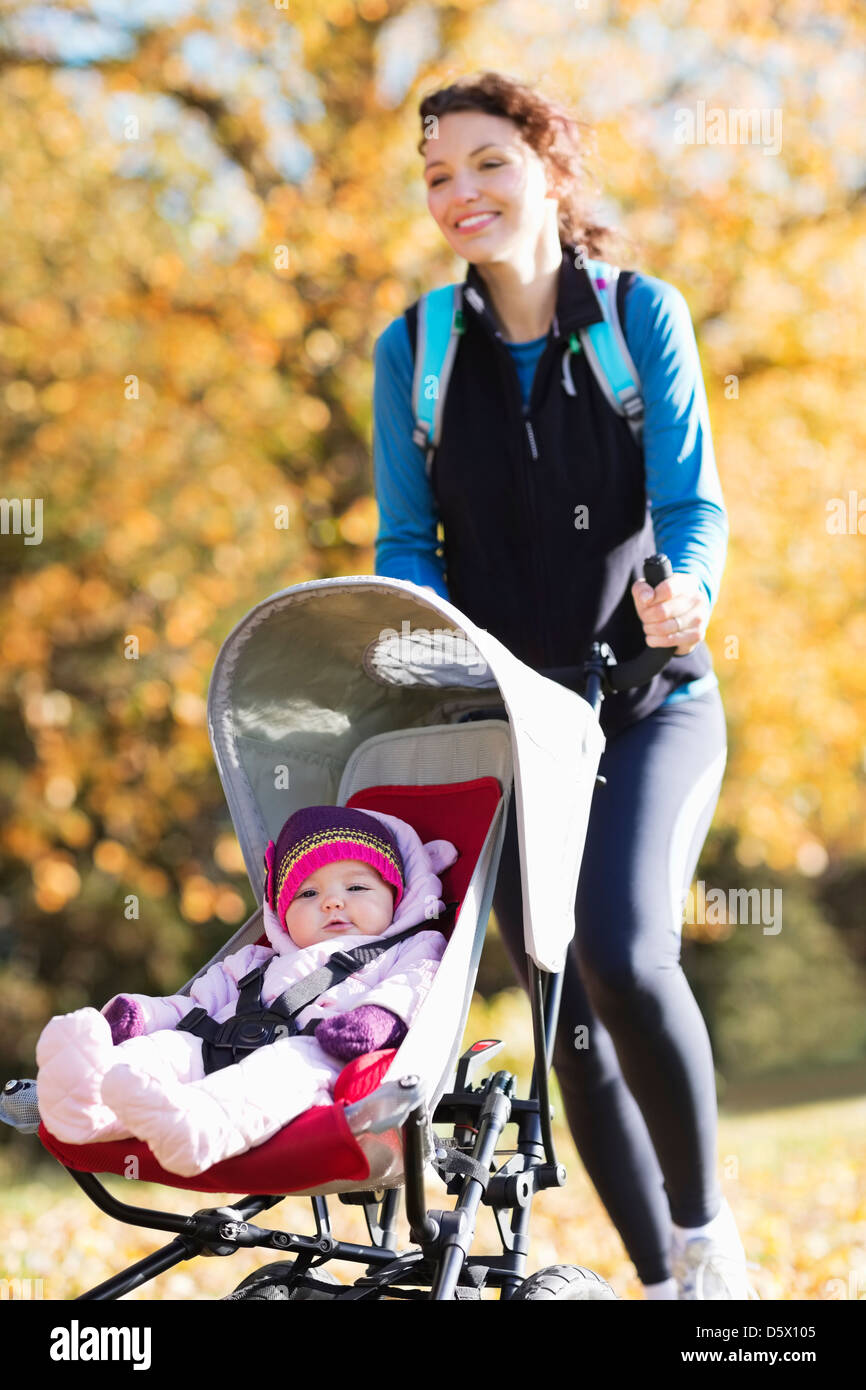 Woman running with baby stroller in park Stock Photo