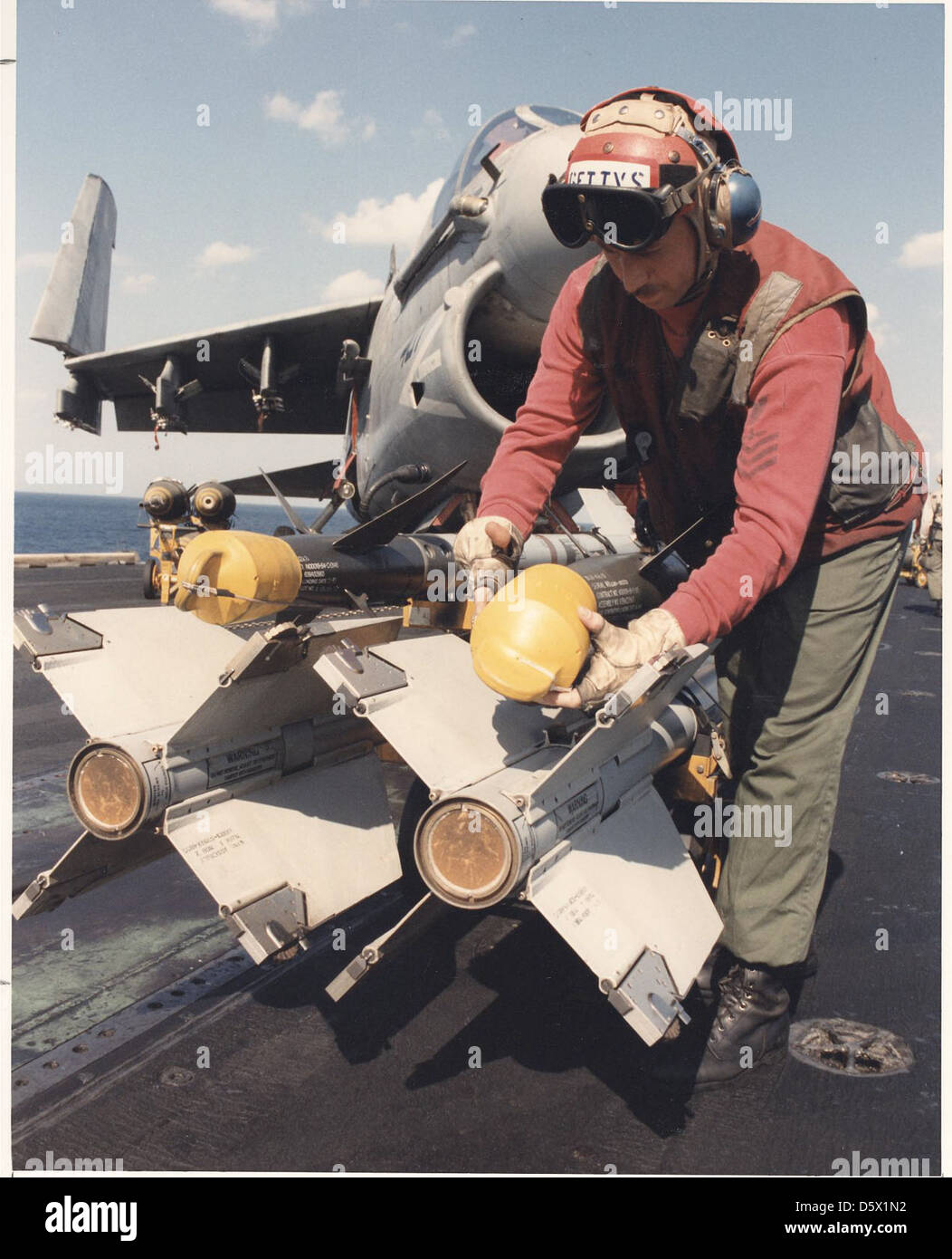 Ordnanceman prepares AIM-9 Sidewinder missile for loading on the flight deck of the USS JOHN F. KENNEDY (CV-67) operating in the Red Sea during 'Operation Desert Storm' with a LTV A-7E 'Corsair II'. Stock Photo