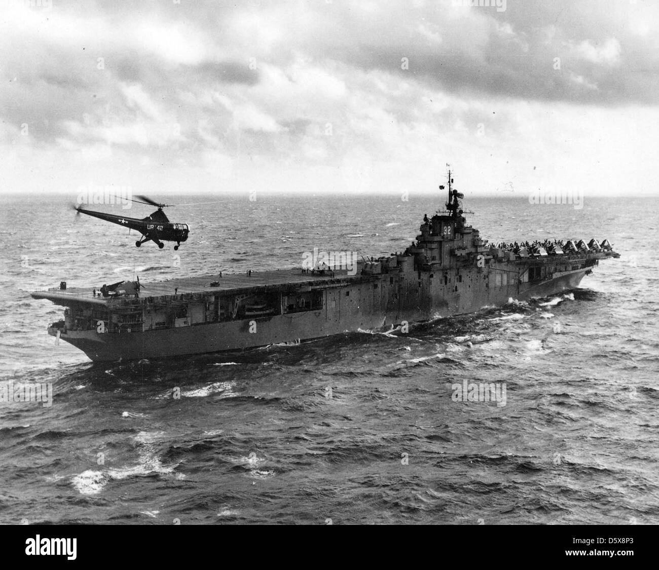 A Sikorsky HO3S-1 'Dragonfly' of Helicopter Utility Squadron (HU) 2 flies over the USS LEYTE (CV-32) during operations at sea. Stock Photo