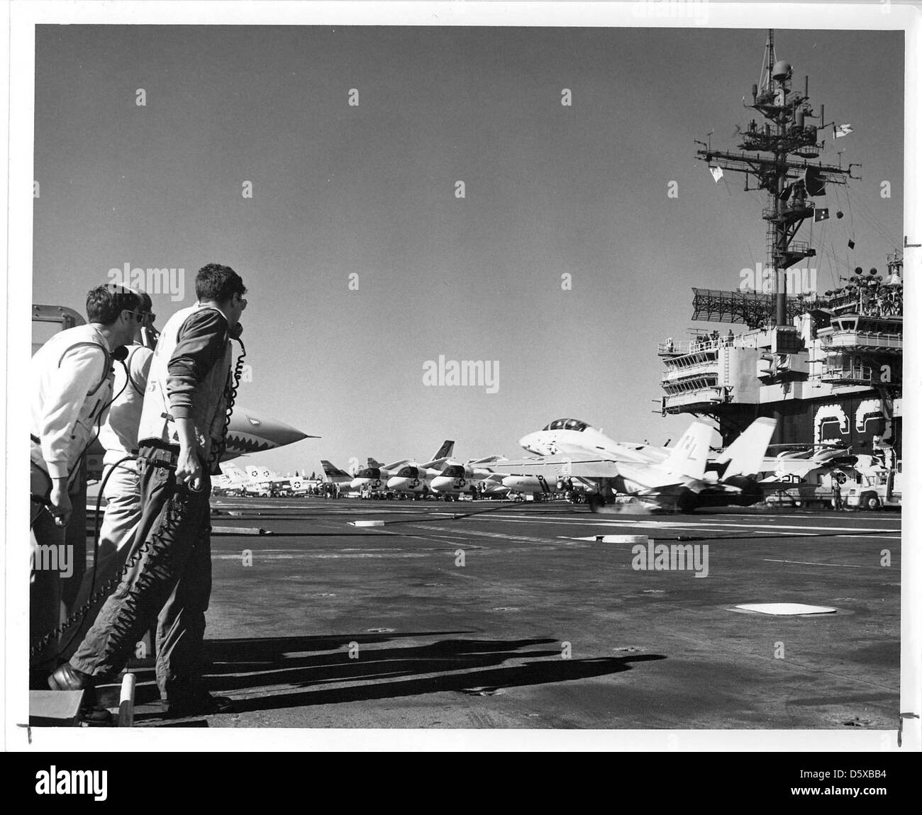 Landing Signal Officers (LSO) observe a Grumman F-14 'Tomcat' coming aboard the USS KITTY HAWK (CV-63). Stock Photo
