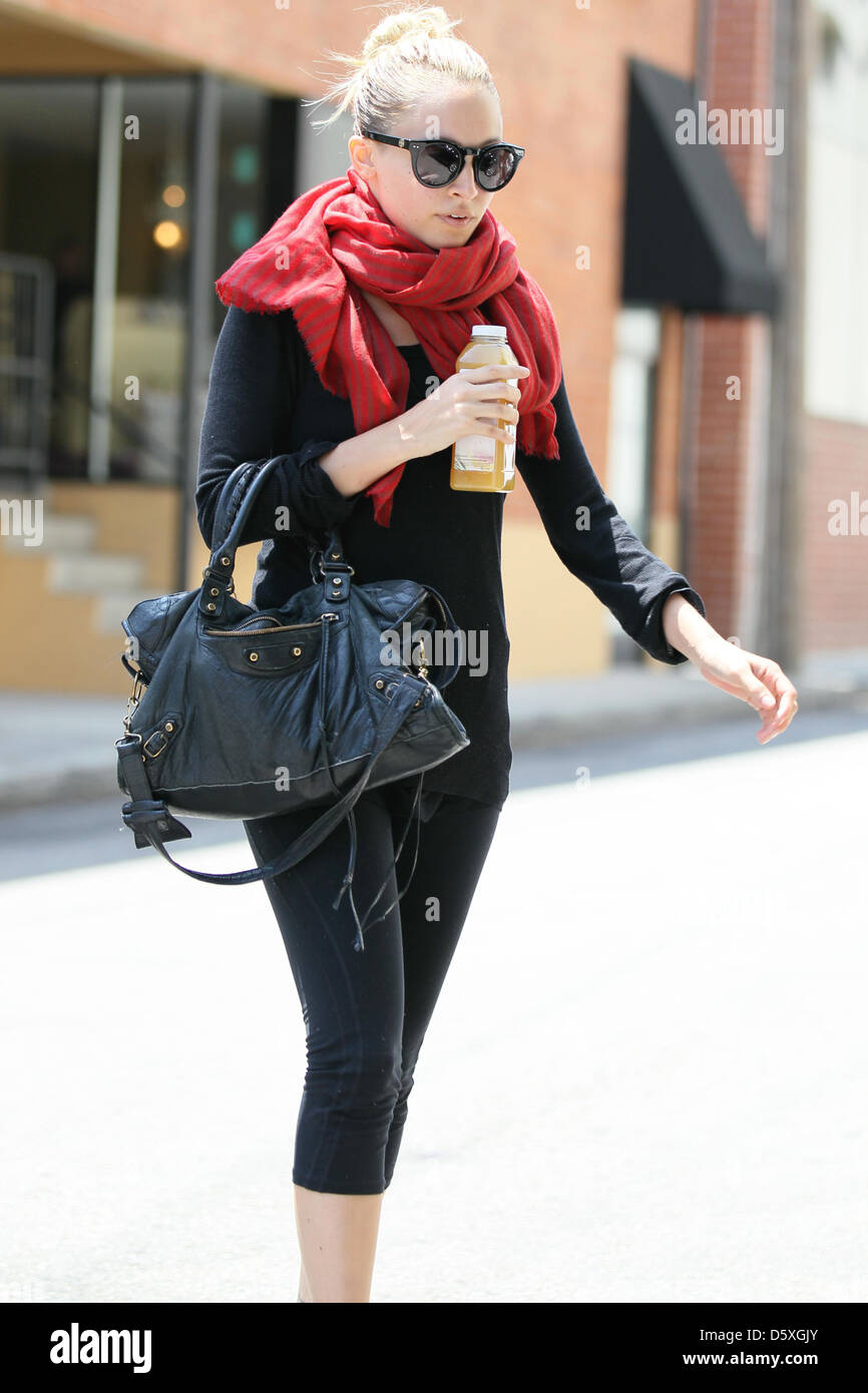 Nicole Richie, wearing a chunky red scarf and toting a Balenciaga