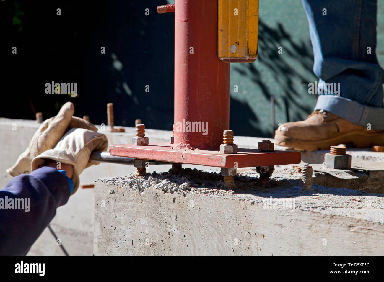 Vertical steel beam is leveled using four bolts spaced from the