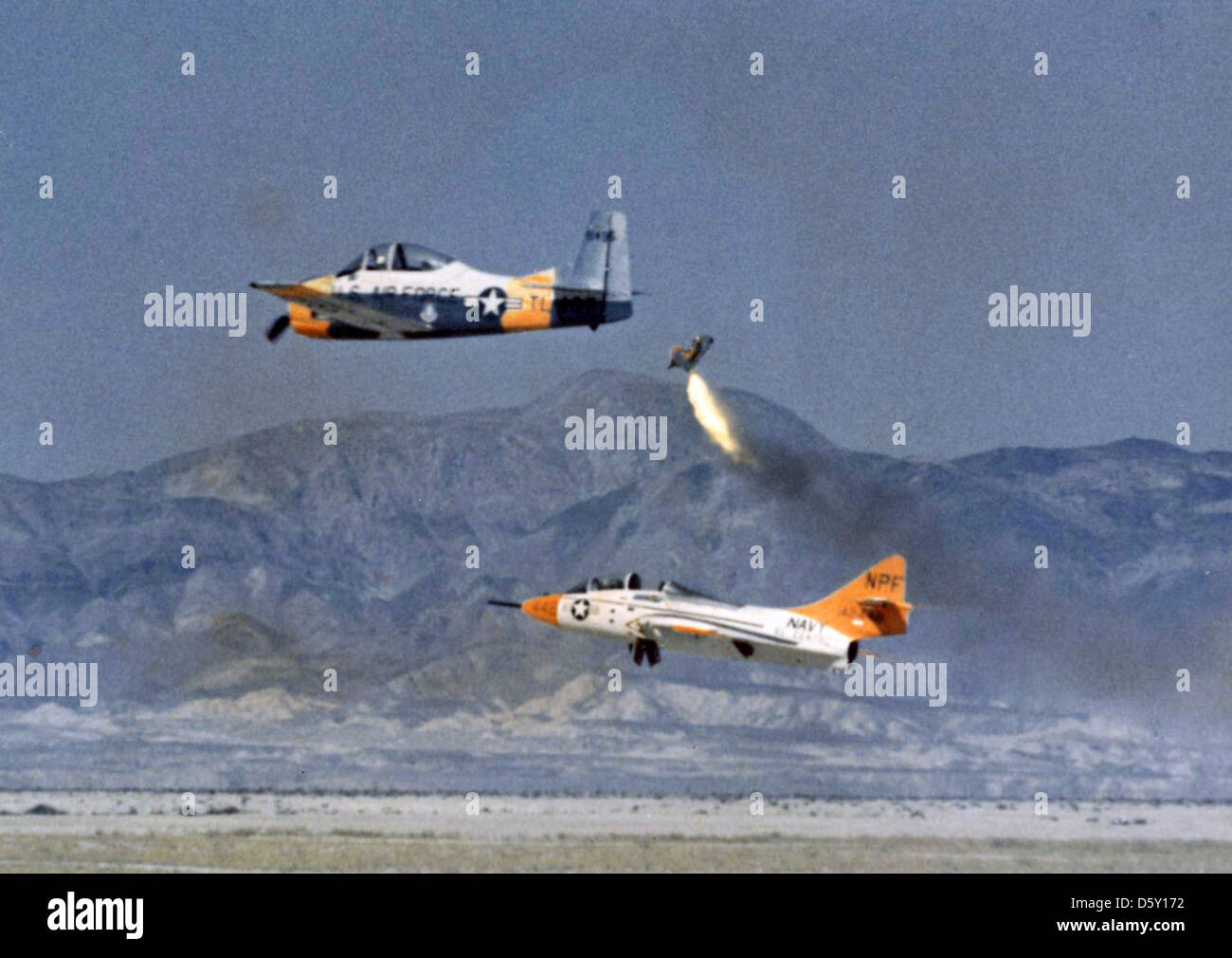Trailed by a USAF North American T-28A 'Trojan', a dummy ejects from the cockpit of a USN Grumman TF-9J 'Cougar' (BuNo 142448) during a demonstration at the U.S. Naval Aerospace Recovery Facility at El Centro, California in 1964. Stock Photo