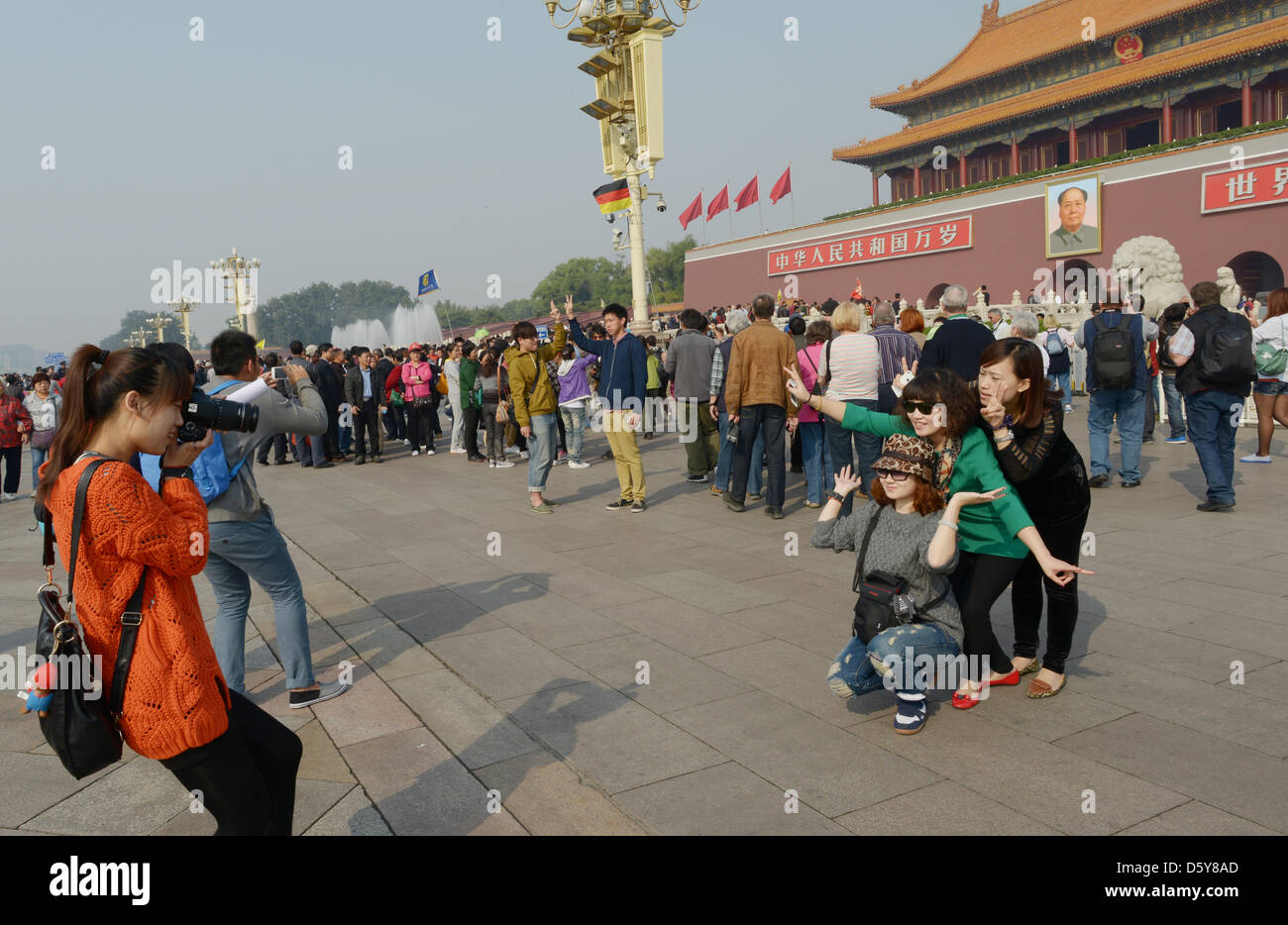 Young tourists take pictures of each other in front of the main entrance to the Forbidden City, which carries a portrait of Mao Zedong, in Beijing, China, 12 October 2012. Photo: Rainer Jensen Stock Photo