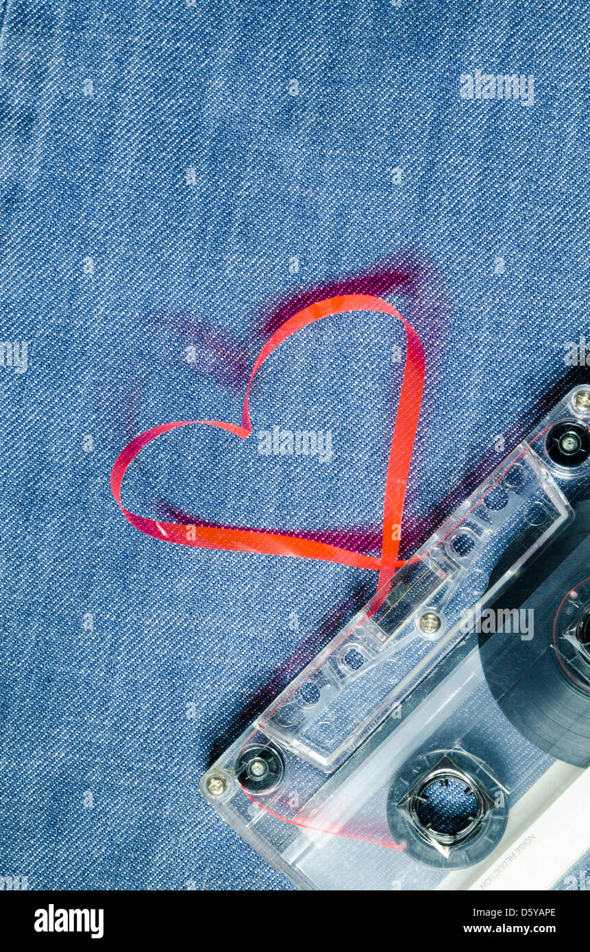 vintage audio cassette on blue jeans with red tape pulled out as heart