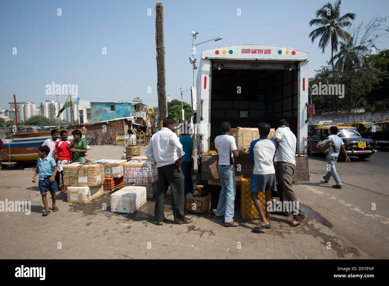 Men load boxes with fresh fish onto a transporter at a small fishing ...
