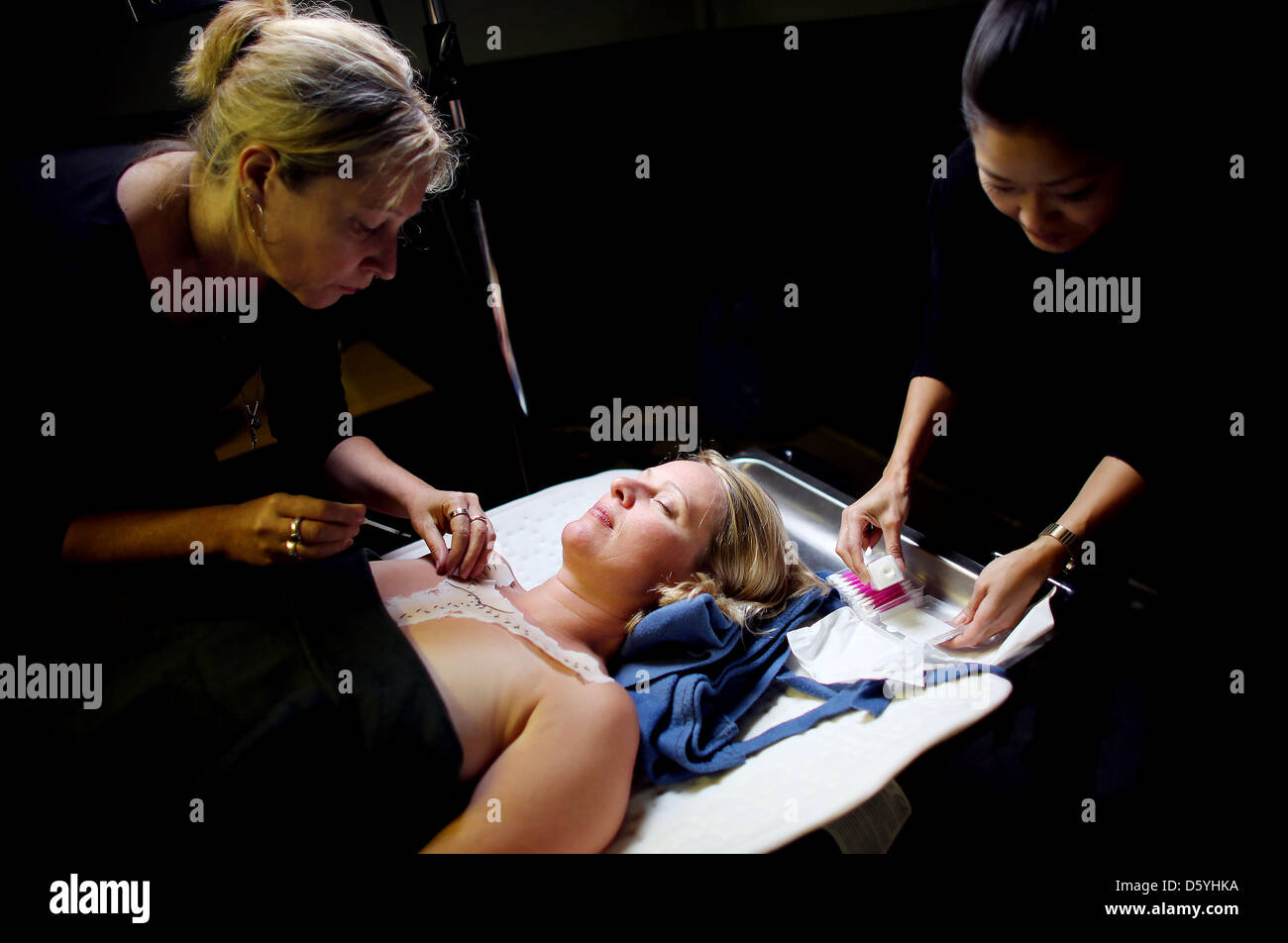 Two make up artists turn an actress into a dead body with autopsy marks in Cologne, Germany, 24 October 2012. The scariness factor in TV crime features is mostly the result of good make up. Photo: Oliver Berg Stock Photo