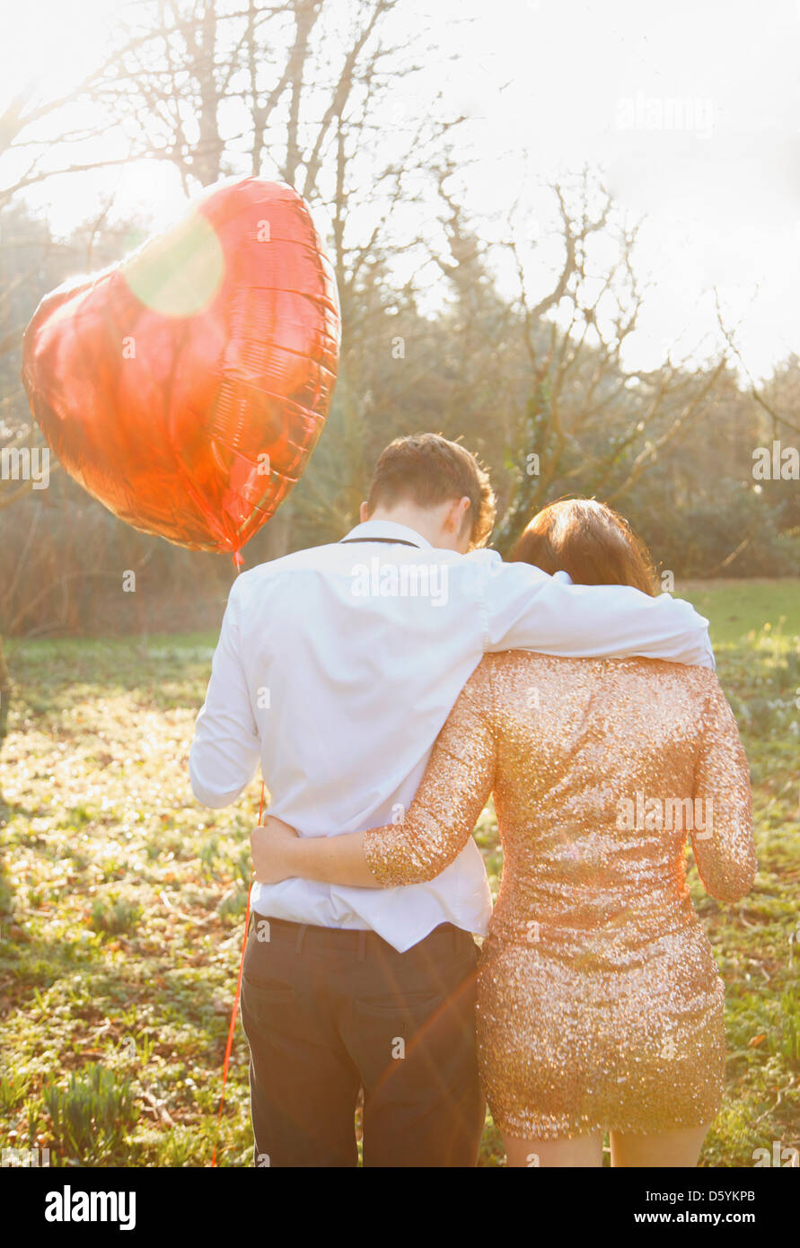 Couple in Park Holding Heart Shaped Balloon, Back View Stock Photo