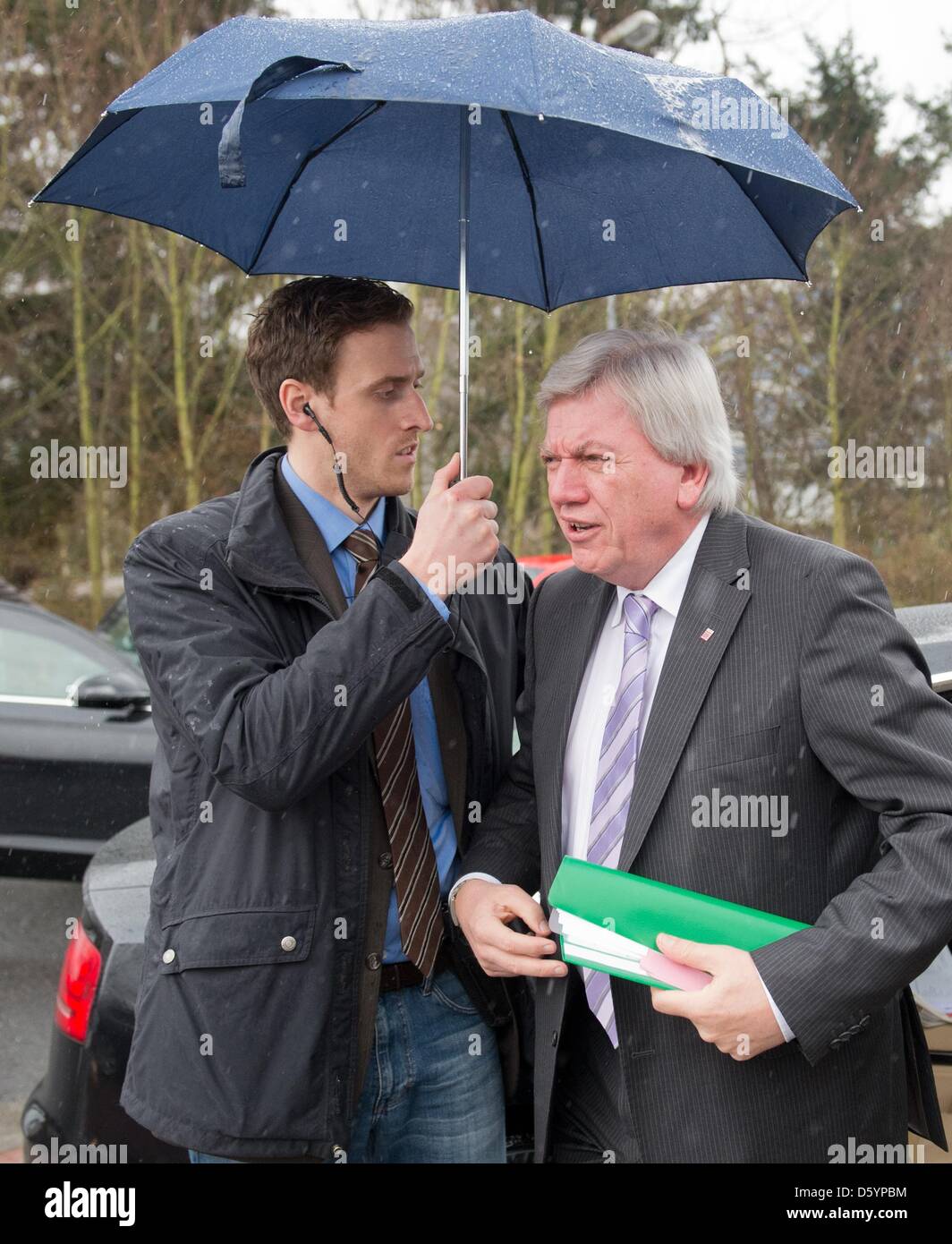 A bodyguard of the LKA protects the Prime Minister of Hesse Volker Bouffier (R) from rain as he