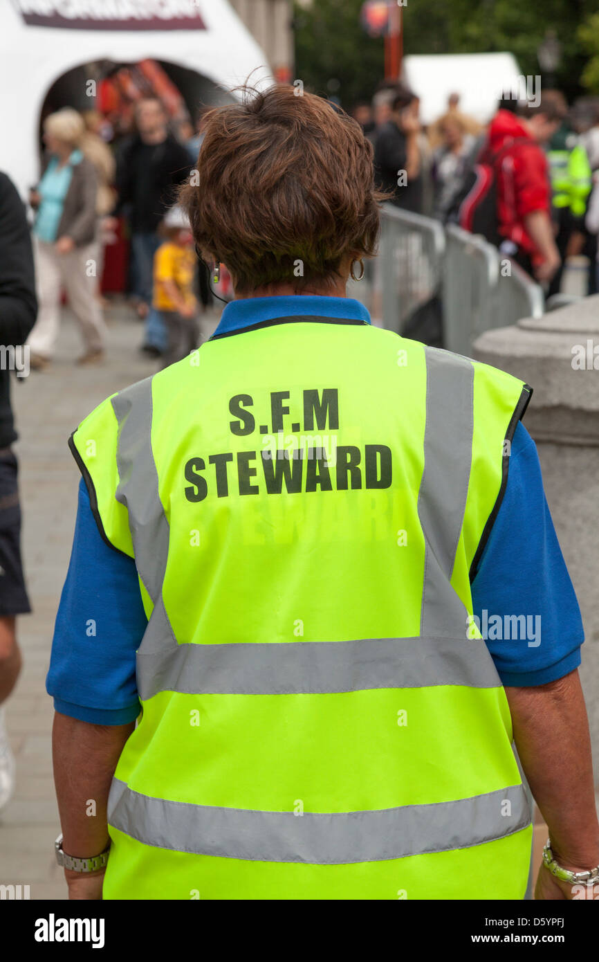rear view woman wearing  of high viz jacket  with words steward Stock Photo