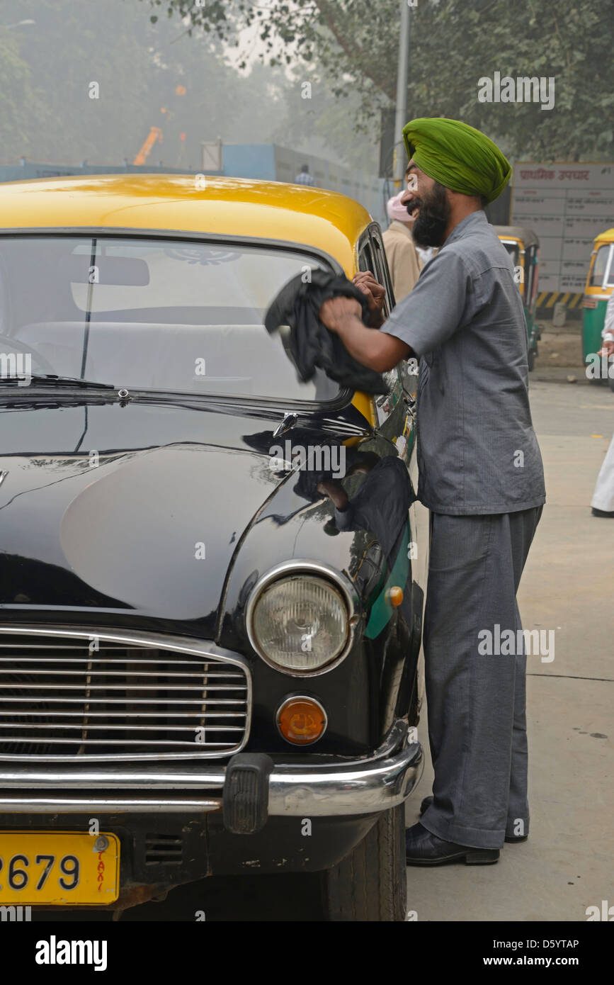 A taxi driver cleans his pride & joy, an Ambassador taxi in New Delhi , India Stock Photo