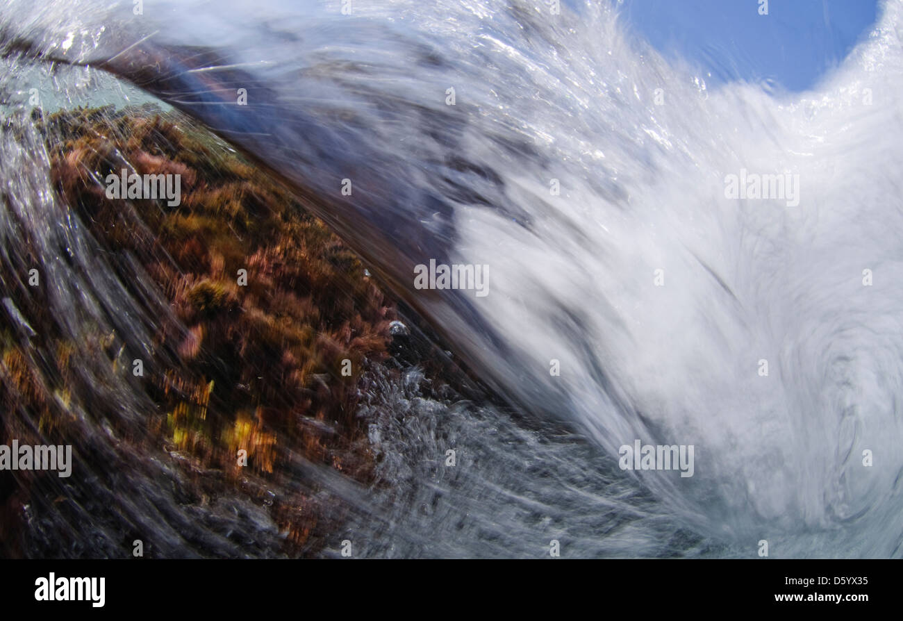 Water abstracts - close up of waves breaking over rocks on a shore Stock Photo