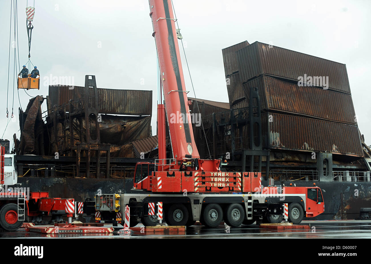 Two workers stand in the cage of a crane to prepare the unloading of ...