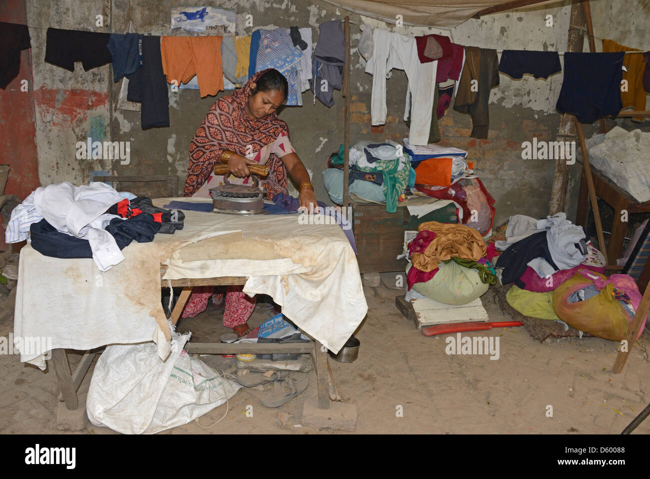 A laundry worker using an iron filled with hot charcoal, ironing a shirt in a side street of New Delhi in India Stock Photo