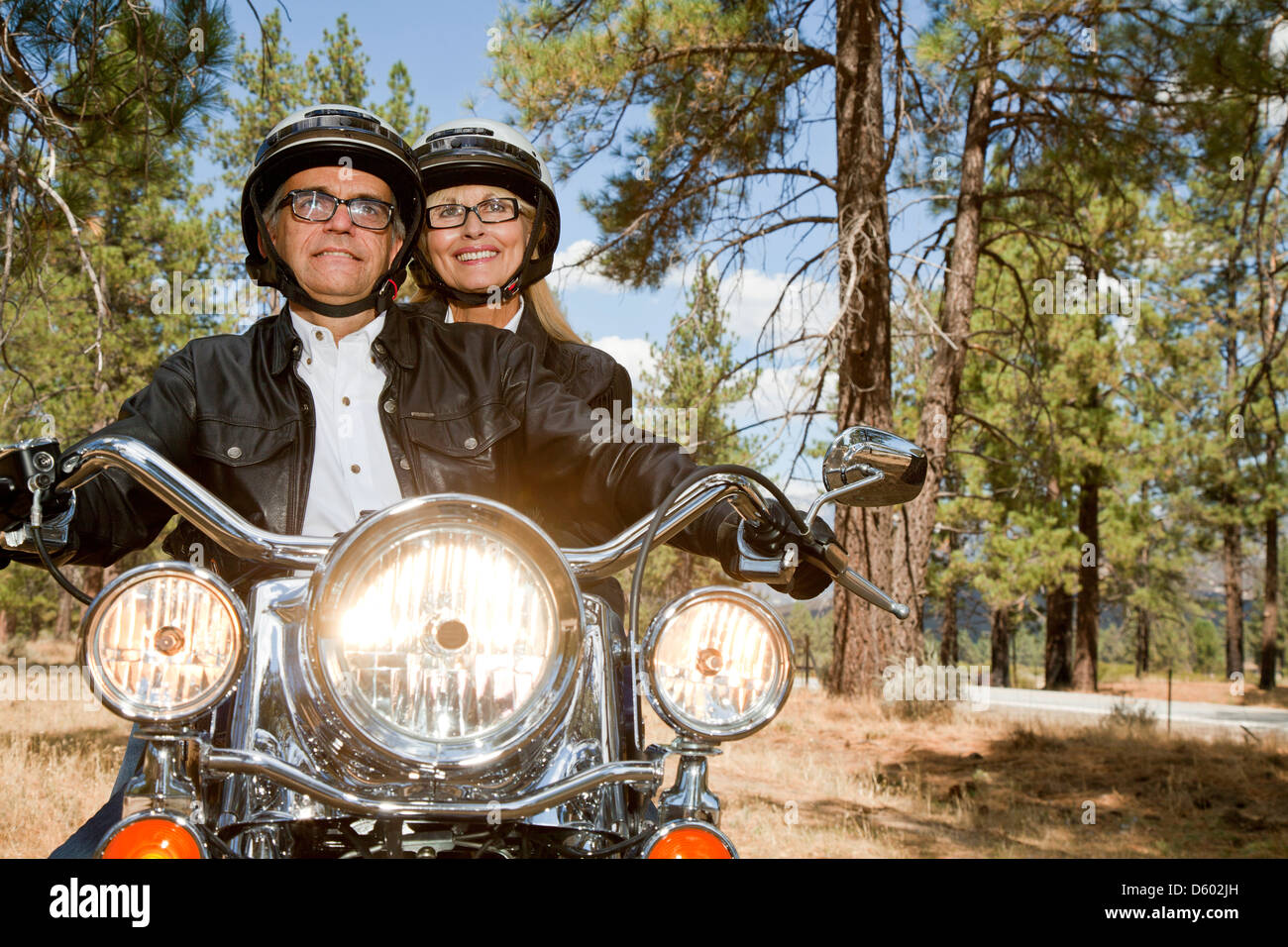 Senior couple riding motorcycle through  forest Stock Photo