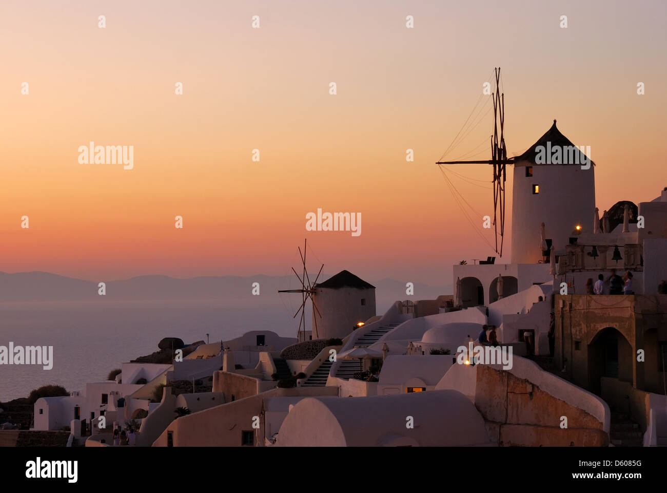 Oia sunset with windmill scenery in Santorini island (Greece). The tourists from all island of Thira (Cyclades, Aegean Sea). Stock Photo