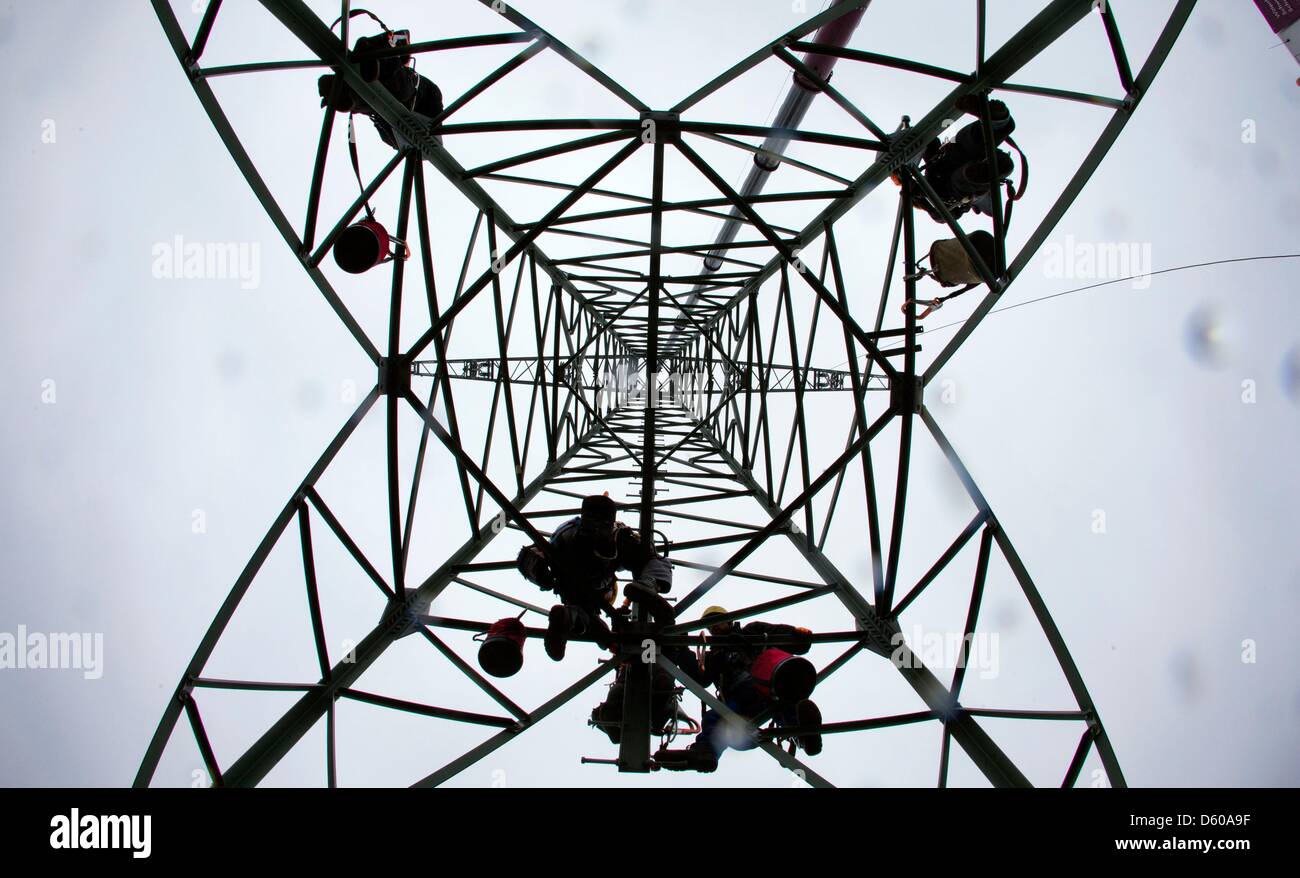 People work on a 110 kilovolt overhead line between Ludwigslust and Hagenow at a freshly installed pylon near Kummer, Germany, 10 April 2013. The energy supplier WEMAG currently modernises and improves the 19km long stretch of power lines and pylons with an investment of 9.4 million euros. Photo: Jens Buettner Stock Photo