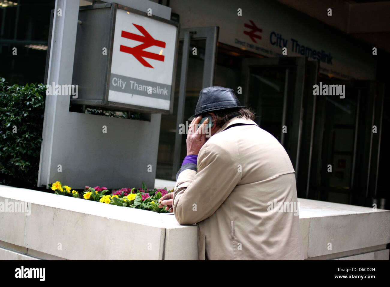 Man on a mobile telephone outside a train station in London Stock Photo