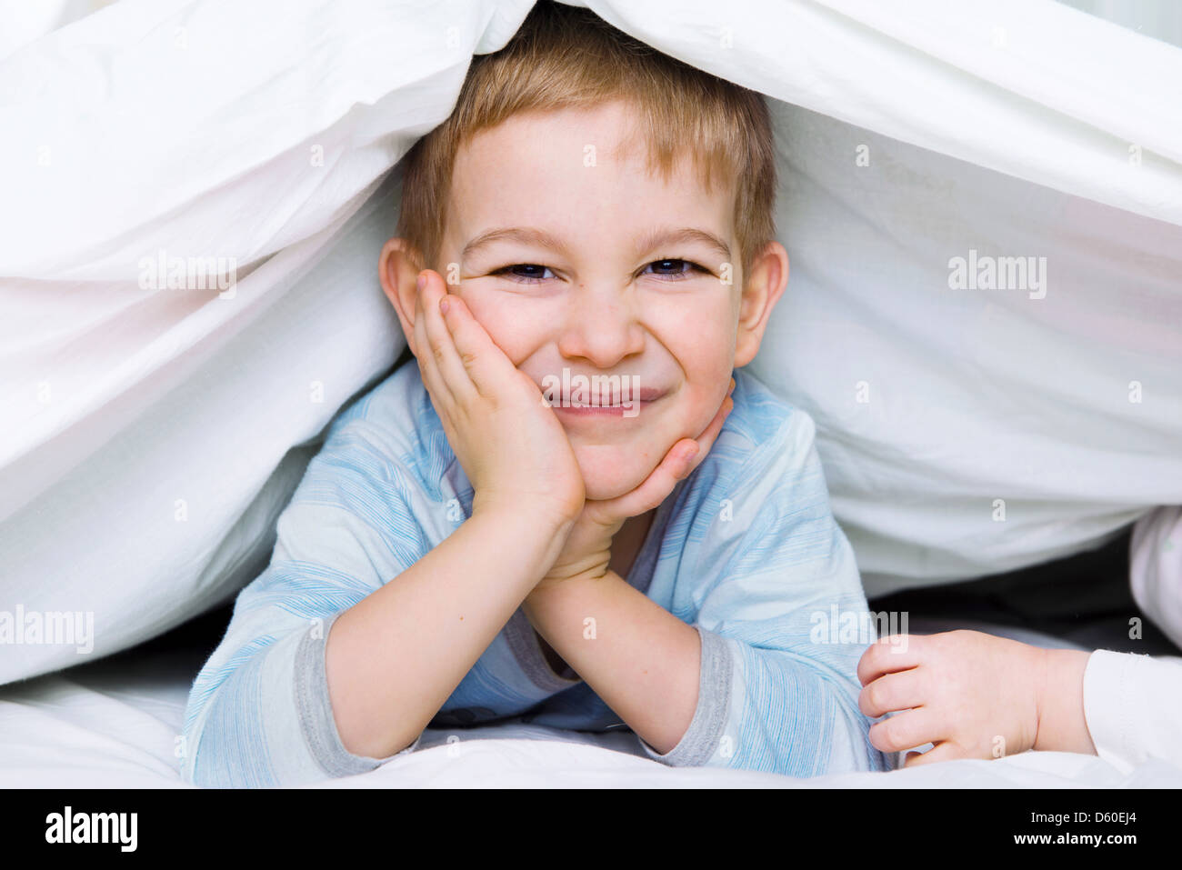 Cute little boy lying under blanket in bed Stock Photo Alamy