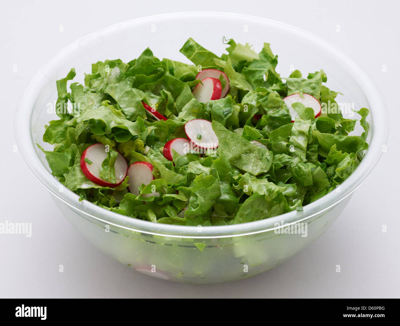 Green lettuce and red radish salad in transparent plastic cup on white Stock Photo