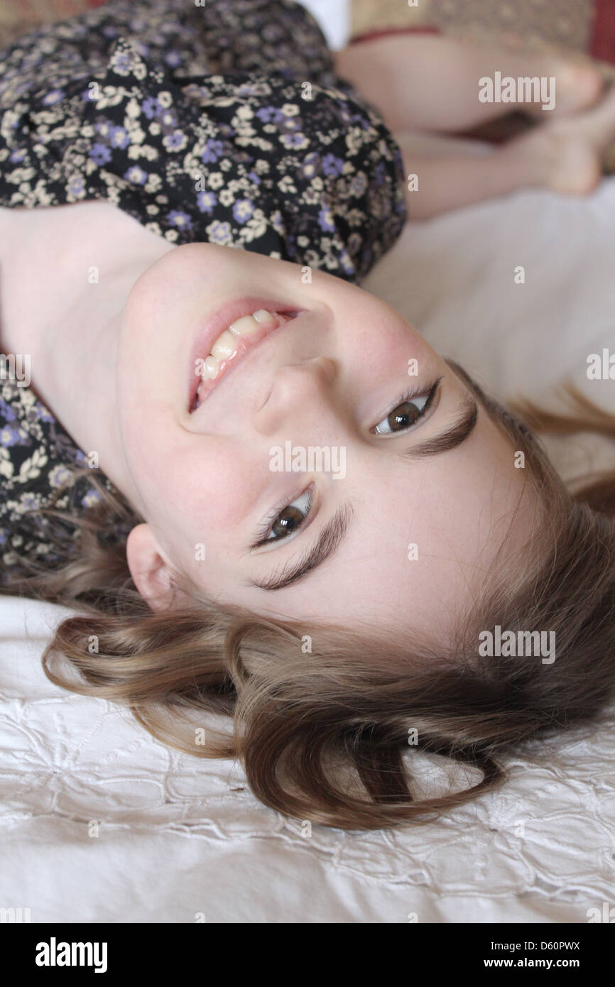 Girl smiling upside down on a bed Stock Photo