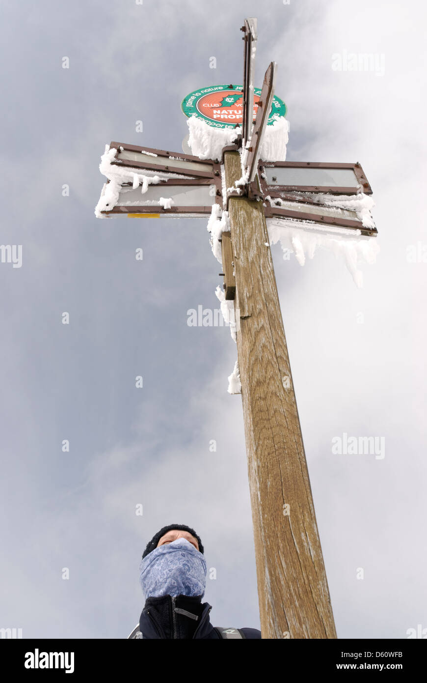 Young man in winter in front of a signpost Stock Photo